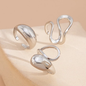 Modern silver abstract ring set with thick droplet and wavy band on aesthetic display