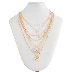 Détail d'un collier doré multicouche avec papillons, perles, étoiles et strass brillants