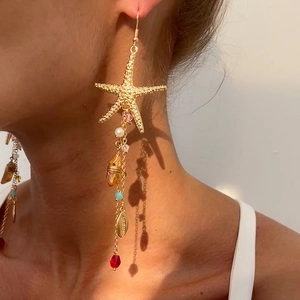 Goldene Seestern-Ohrhänger mit Muschelanhängern und bunten Kristallen an Model
