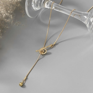 Detailed close-up of gold snake chain necklace with a unique knot pendant and bead charm