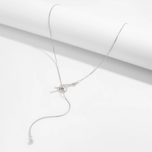Macro view of silver snake chain with irregular twist buckle and droplet pendant necklace