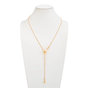 Detail of a gold Y-shaped necklace featuring a knotted center and a metal ball pendant