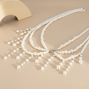Detailed view of layered white pearl body chain with elegant silver metal tassels