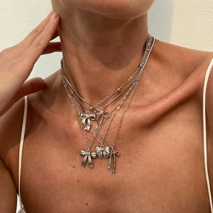 Ensemble de 5 colliers à pendentif nœud argentés superposés portés par un mannequin