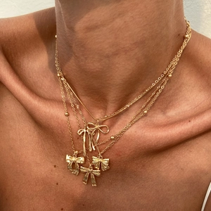 Collier multi-rangs doré avec pendentifs nœuds élégants et chaînes superposées fines