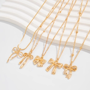 Détail de cinq colliers à nœuds dorés assortis avec des chaînes serpent et perlées