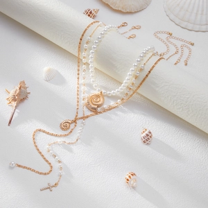Detalle del collar de perlas de varias capas con conchas doradas y colgante de cruz