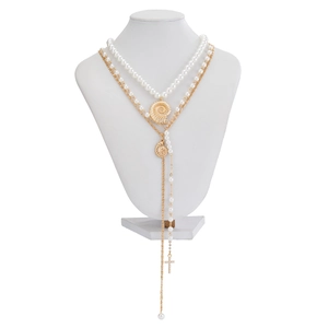 Detalle de collar multicapa dorado con concha y perlas sobre un maniquí blanco