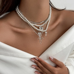 Gros plan d'un collier multicouche avec perles et nœuds argentés sur modèle en satin