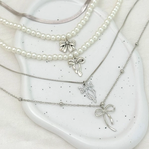 Détail de colliers de perles avec pendentifs nœuds sur un plateau en céramique