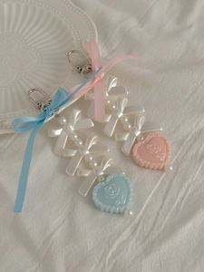 Detail of pink and blue ribbon bow keychains with pearl beads and embossed heart charms