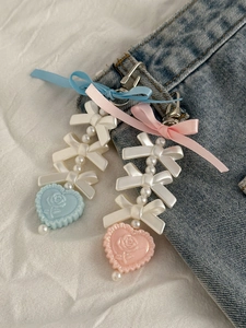Close-up of pink and blue ribbon pearl heart charms attached to denim jeans pockets