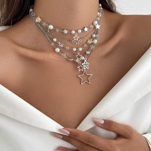 Détail d'un collier multicouche à étoiles et perles porté sur une chemise en satin blanc