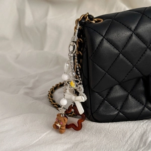 Détail des breloques ours et étoile sur un sac matelassé noir avec chaîne dorée