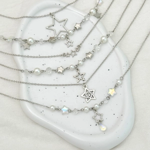 Détail de pendentifs étoile argentés avec perles et cristaux sur un plateau céramique
