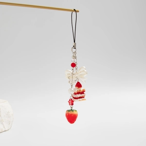 Detail of sweet strawberry cake keychain with white ribbon bow and pearl bead accents
