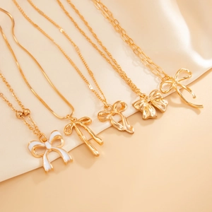 Détail de cinq colliers nœuds plaqués or sur un fond élégant en satin crème