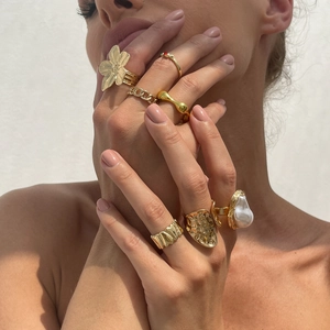 Κοντινό πλάνο με χρυσά boho δαχτυλίδια με μπαρόκ μαργαριτάρι και φλοράλ σχέδια