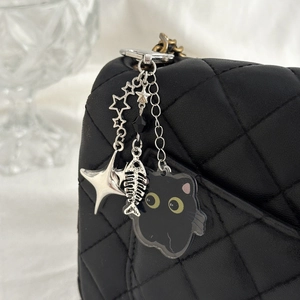 Pendentif chat noir et arête de poisson en acrylique sur un sac matelassé noir