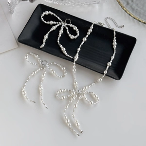 Detailed view of pearl bow necklace set with silver extender chain on elegant tray