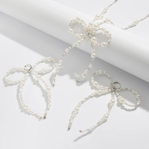 Elegant white pearl bow necklace and earring set displayed on a white podium