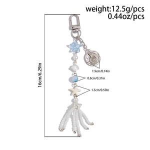 Detail view of ocean style keychain with star beads, shells and white tassel length 16cm