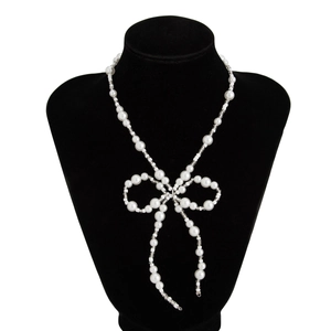 Detail of white faux pearl choker necklace featuring a central elegant bow design