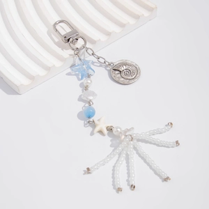 Nautical keychain detail with blue star bead, white starfish, and shell charm on fringe