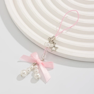 Detail of pink silk bow keychain with faux pearls and silver star pendant charm