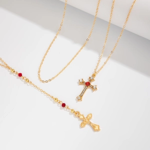 Détail de colliers croix dorés avec gemmes rouges et cristaux blancs sur doubles chaînes