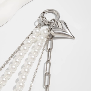 Makroaufnahme von Herzanhänger mit Perlenquasten und silberner Kette als Taschen-Accessoire