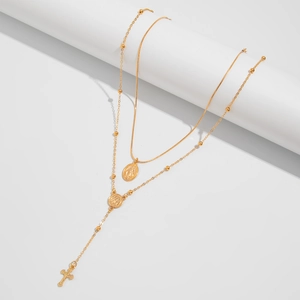 Détail de colliers dorés superposés avec médaille de la Vierge et petite croix