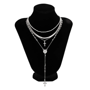 Detalle de collares plateados a capas con colgantes de cruz y virgen en busto negro
