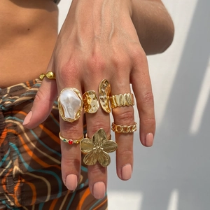 Λεπτομέρεια από χρυσά boho δαχτυλίδια με μπαρόκ πέρλα και φλοράλ σχέδιο από κράμα