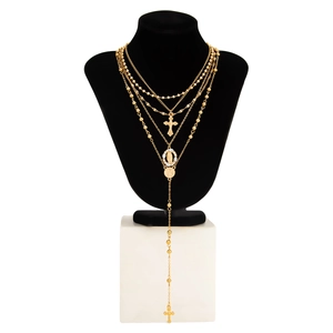 Détail de colliers dorés superposés avec croix et médaille religieuse sur un buste en velours