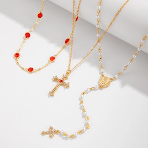Vue détaillée du lot de trois colliers dorés avec pendentifs en croix et perles blanches