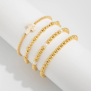 Detail von 4-teiligem Goldperlen-Armband-Set mit weißem Marmor-Kreuz-Anhänger auf Display