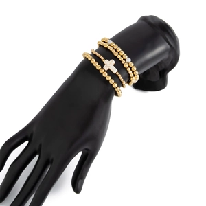 Detailansicht eines dreiteiligen goldenen Perlenarmband-Sets mit weißem Marmorkreuz