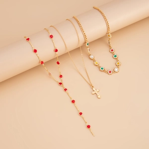 Détails d'un ensemble de trois colliers dorés superposés avec croix et pendentifs fleurs