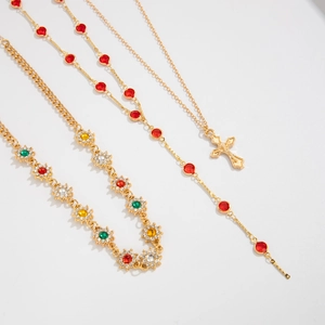 Détail de l'ensemble de trois colliers dorés avec pendentif fleur en cristal et croix