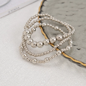 Makroaufnahme eines silbernen mehrlagigen Perlenarmband-Sets mit Kreuzen auf einem Tablett