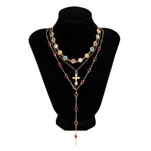 Détail de colliers dorés superposés avec fleurs colorées et pendentif croix en chaîne Y