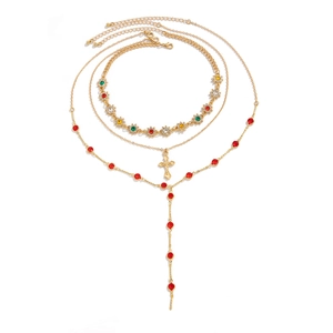 Détail du collier doré multicouche avec strass colorés et pendentif croix