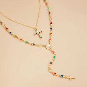 Détail d'un collier doré double épaisseur avec des pierres colorées et pendentifs croix