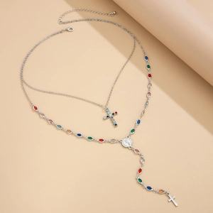 Détails d'un collier argenté à deux rangs avec gemmes colorées et pendentifs croix
