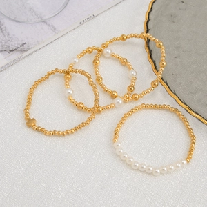 Detailaufnahme eines 5-teiligen goldenen Perlenarmband-Sets mit eleganten weißen Perlen