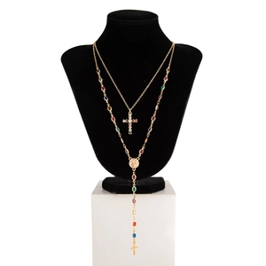Dettaglio della collana dorata a due strati con pietre colorate e ciondolo a croce