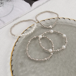 Detailaufnahme des vierteiligen Armband-Sets mit Silberkreuz und Imitationsperlen