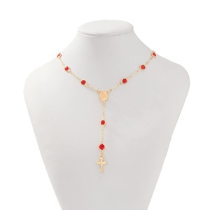 Détail du collier chapelet doré avec cristaux rouges et pendentif croix sur un mannequin