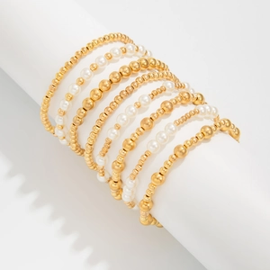 Detail von mehrlagigen Goldperlenarmbändern und Perlenimitationen auf weißem Ständer